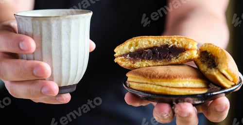 Preview: Person offering japanese dorayaki and green tea.