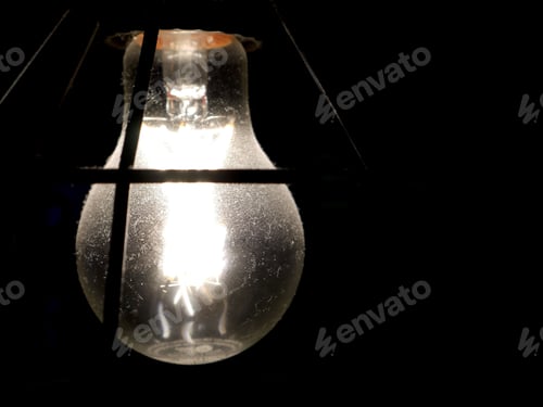 Preview: Close-up image of a solitary light bulb in a dark environment