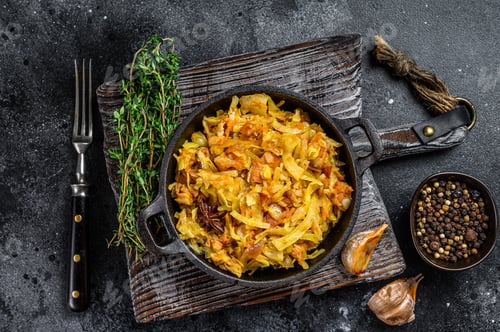 Preview: Stewed cabbage Bigos with mushrooms and sausages. Black background. Top view