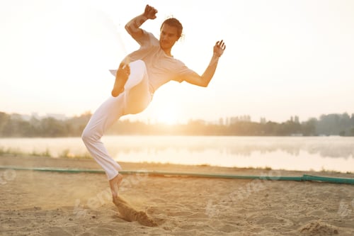 Preview: Athletic capoeira performer workout training on the beach sunris
