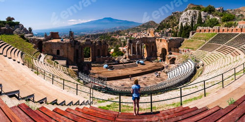 Preview: Panoramic photo of a tourist visiting Teatro Greco aka Taormina Greek Theatre, with Mount Etna Volca