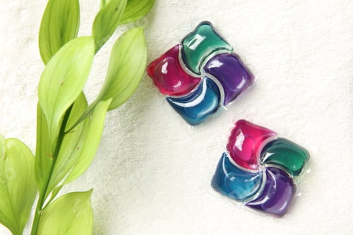 Preview: Laundry detergent pods and green branch on towel, flat lay