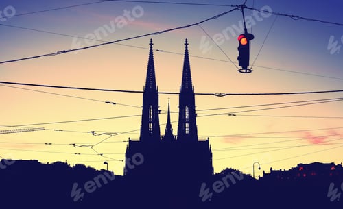 Preview: Silhouette of the Votive Church and stoplight at dusk.