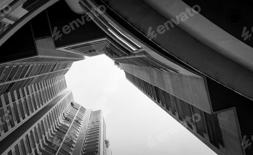 Preview: Bottom view of skyscraper building against gray sky and cloud. Looking up view in apartment building