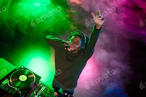 Preview: overhead view of professional african american DJ with microphone and sound mixer in nightclub