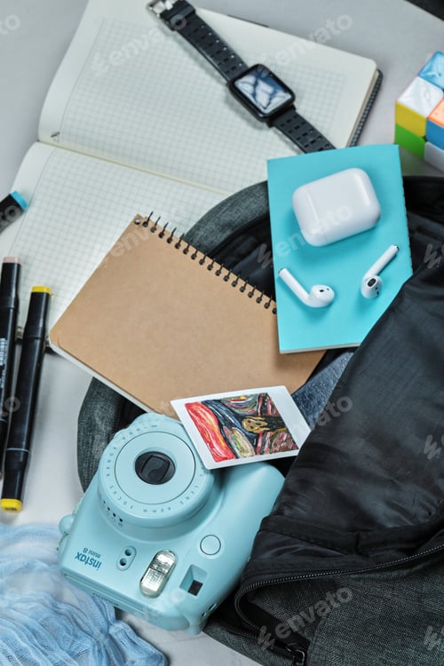 Preview: A backpack full of notebooks, polaroid, watch, pencils on the blue and white background