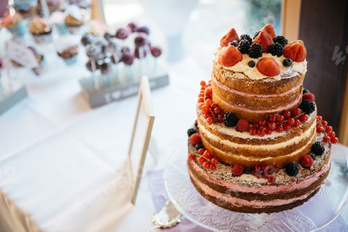 Preview: Closeup shot of a tiered cake decorated with fruits on the table with blur background