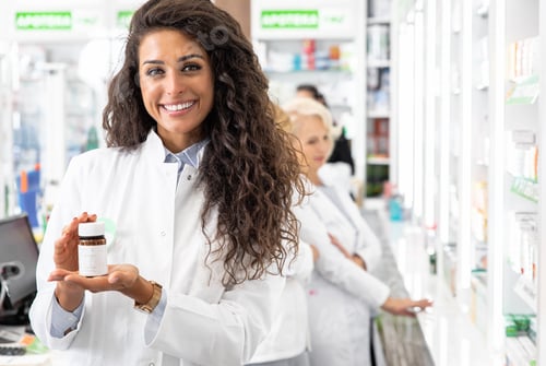 Preview: Portrait of female pharmacist showing medicine box to the camera.