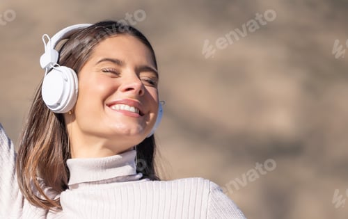 Preview: Side portrait of happy woman with headphones listening to audio with defocused background