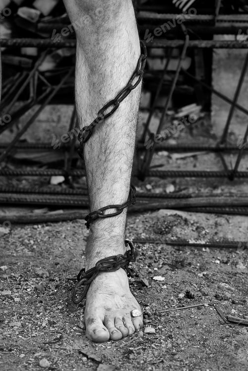 Preview: Close-up shot of barefoot legs tied up with old chain