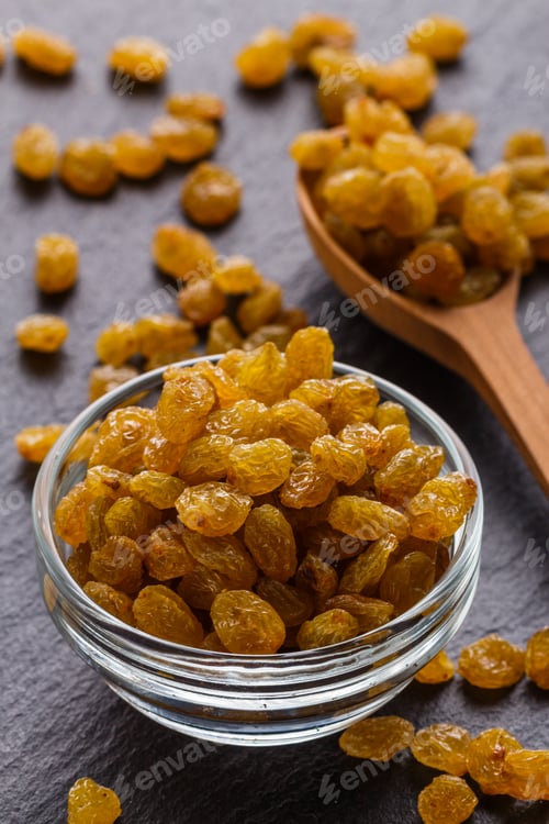 Preview: golden raisins on a dark stone background