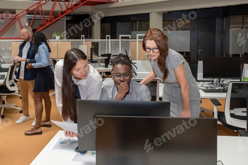 Preview: three multi-ethnic business partners working on a project on a computer in a coworking space