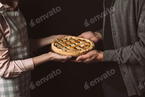 Preview: cropped shot of couple holding homemade pie together isolated on black