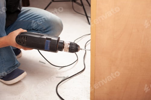 Preview: Man twists screw into cupboard