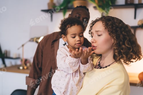 Preview: Cute child opening hands while carried by loving mother together with father in room