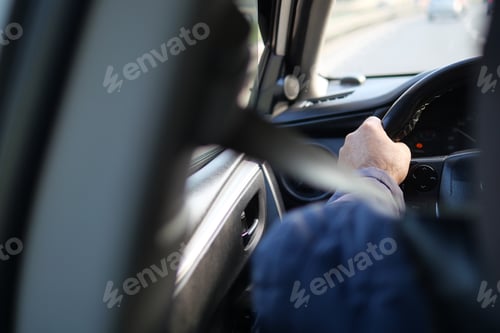 Preview: Driving on a Road with a Seatbelt: View from Backseat, Focus on Driver's Hand on Steering Wheel