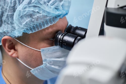 Preview: Male Surgeon Examining Patient Using Surgical Microscope