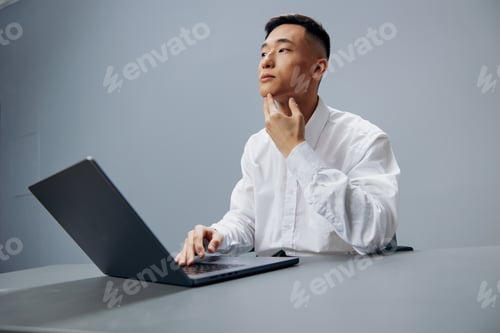 Preview: manager working on a laptop sitting at a table in the office executive