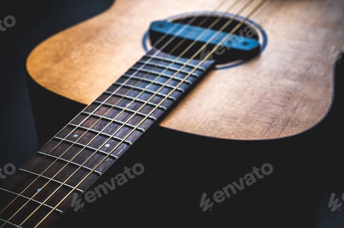 Preview: Acoustic guitar, music instrument resting against a dark black background with copy space