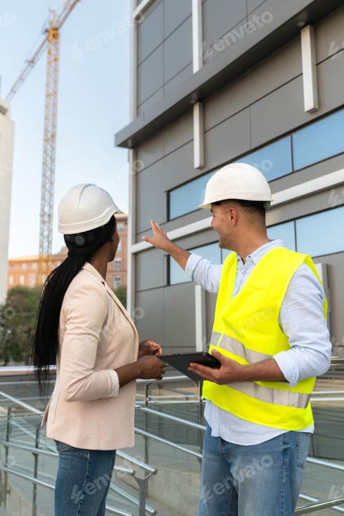 Preview: Two diverse Architect and construction engineer discussing building project at construction site