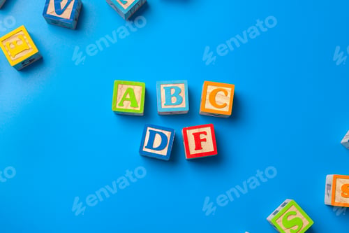Preview: Abcdf. Wooden colorful alphabet blocks on blue background, flat lay, top view