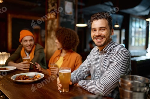 Preview: Happy smiling man sitting at sports bar counter desk looking at camera