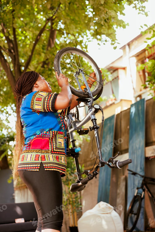 Preview: Woman reattaching bicycle wheel in yard