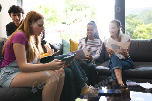 Preview: Teen friends sitting on sofa sharing music and enjoying vinyl records together