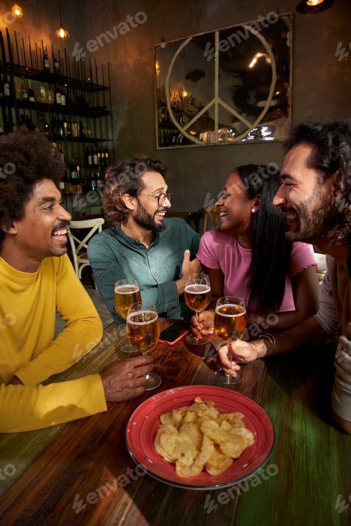 Preview: Young people laughing and drinking in a pub. Group of friends celebrating a party together