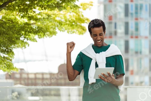 Preview: Portrait of overjoyed African American man holding digital tablet, receiving good news