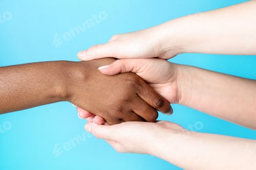 Preview: Stop racism. People of different skin colors holding hands on light blue background, closeup