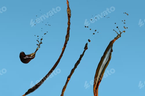 Preview: Splashes of black coffee isolated on blue background