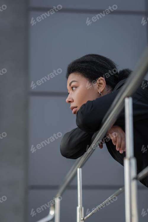 Preview: Young multiracial woman with apathy looking away near railing outdoors