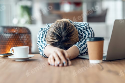 Preview: Exhausted young business woman who has fallen asleep while working wirh laptop in living room