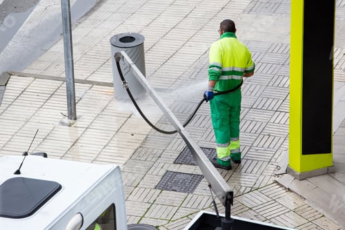 Preview: Worker cleaning a street sidewalk with water