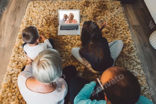 Visualização: Família de quatro pessoas conversando com os avós durante uma videochamada em um tablet digital