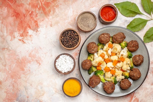 Preview: top view broccoli and cauliflower salad and meatball on plate different spices in small bowls on
