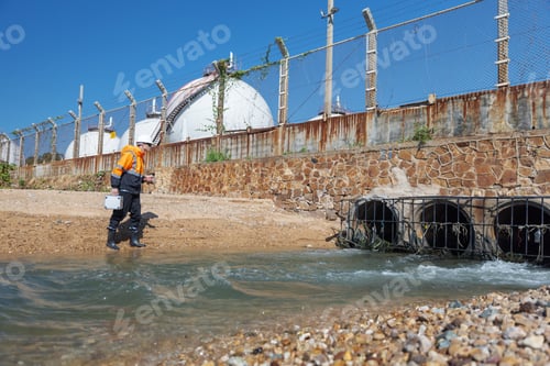 Preview: An environmental engineer inspects water flow near an industrial drainage outlet.
