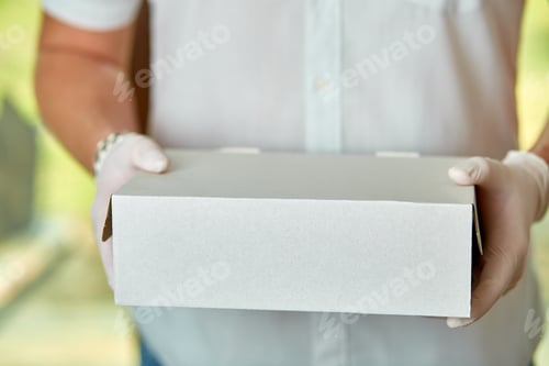 Preview: Courier, delivery man in medical latex gloves and mask safely delivers