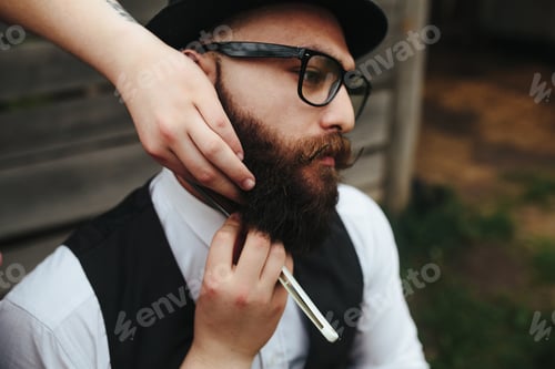 Preview: barber shaves a bearded man in vintage atmosphere