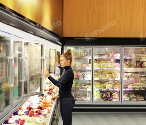 Preview: Woman Choosing Frozen Food From A Supermarket Freezer. Purchasing A Packet Of Meat At The