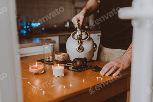 Preview: a young man makes tea and pours boiling water over Chinese tea puerh, candle lights