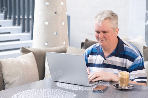 Preview: middle-aged man working on a laptop in a cafe
