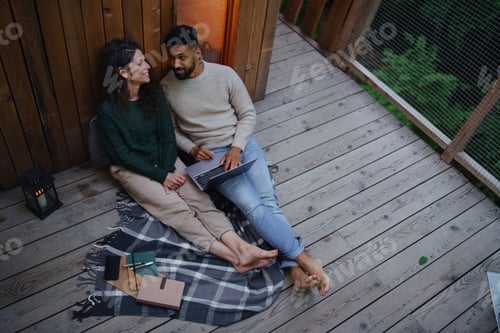 Preview: Top view of happy couple with laptop resting outdoors in a tree house, weekend away and remote