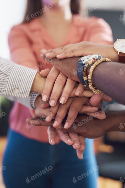 Preview: Cropped shot of a group of businesspeople joining hands in solidarity in a modern office