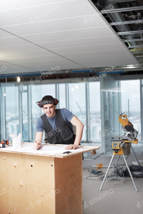 Preview: Young architect working on his plans while at a construction site