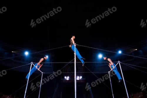 Preview: low angle view of gymnasts performing on horizontal bars in circus