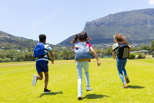 Preview: Three children are running joyfully across a grassy field on a sunny day