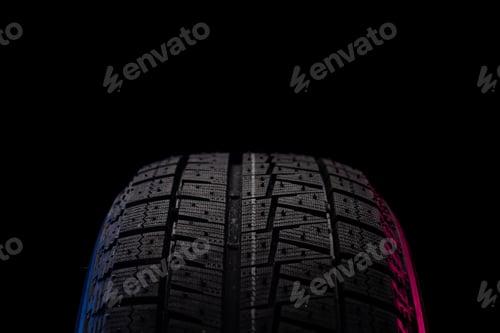 Preview: tire with a tread for driving on ice and snow on a black background with an image blue red