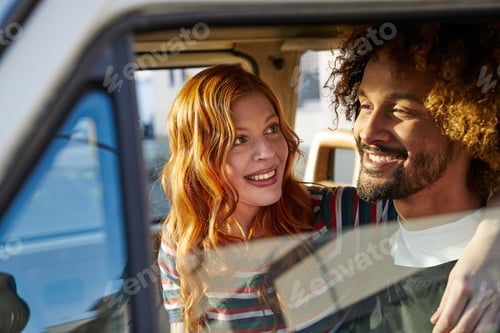 Preview: Smiling young woman looking at boyfriend in a car